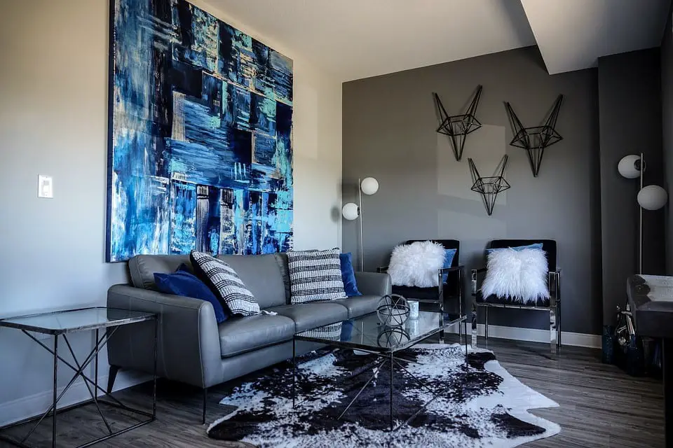 The living room of a house designed in blue colors with attractive wall hanging and paintings