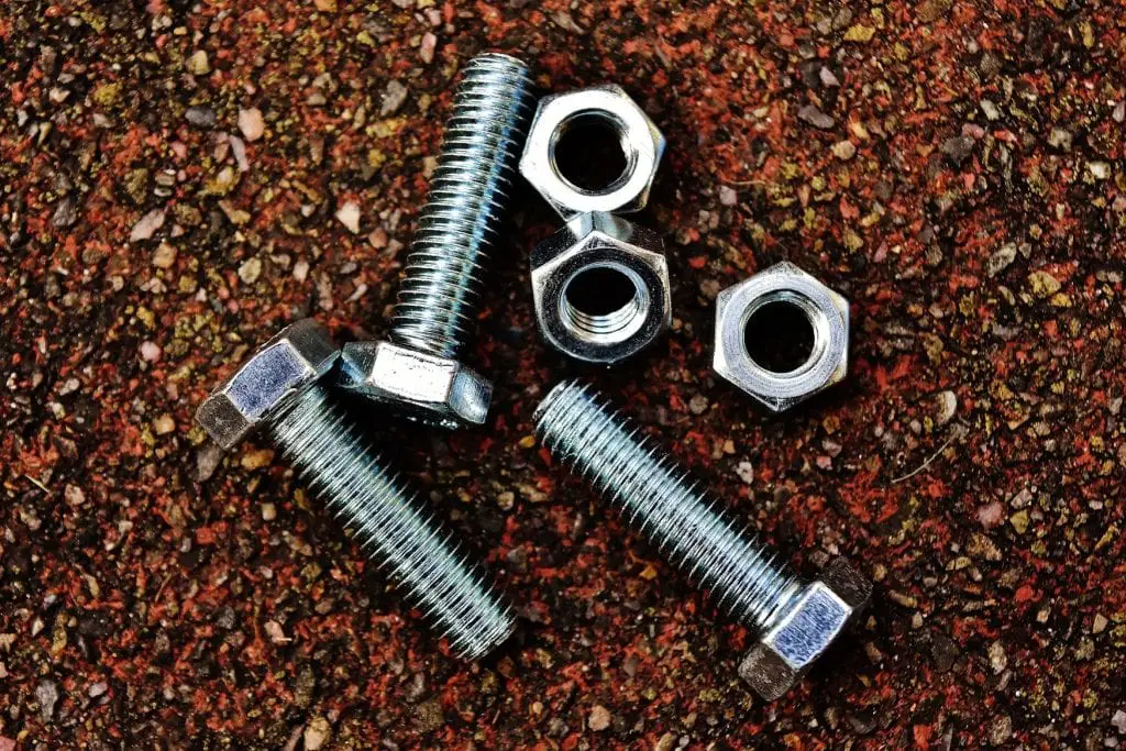 3 nuts and 3 bolts lie on an uneven surface