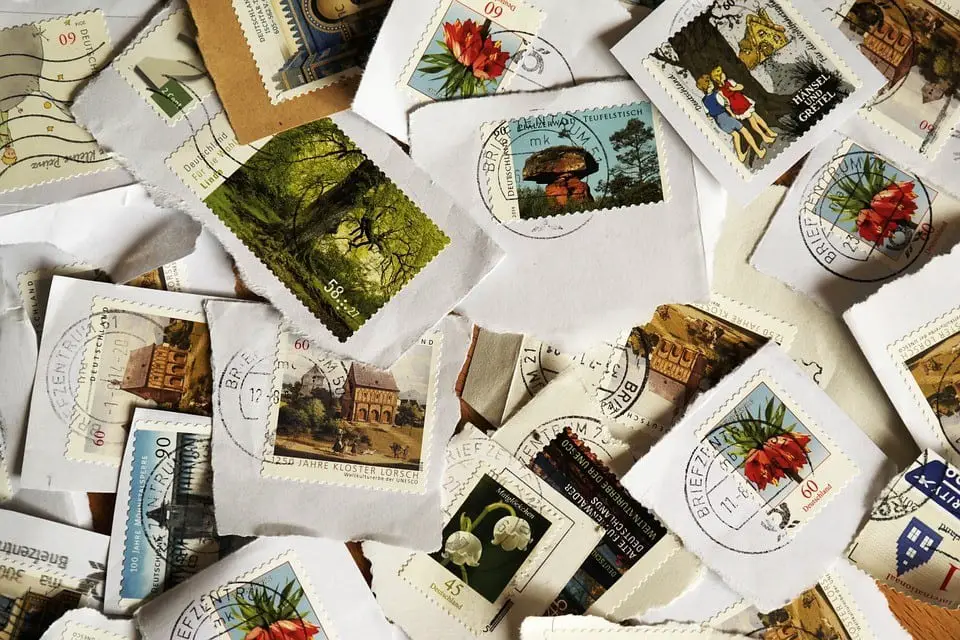 Multiple colorful postage stamps from different countries scattered together on a table.